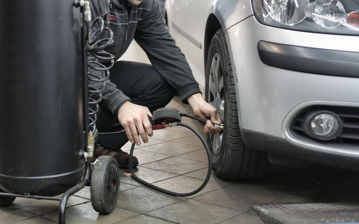 Technician checking tyre pressure on a car